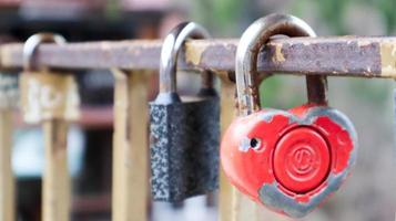 serrure rouge minable en forme de coeur. concept d'amour de la Saint-Valentin. un cadenas accroché à une balustrade en métal est un signe d'amour éternel. la tradition d'accrocher un château avec une clôture photo