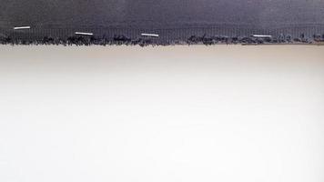 fond blanc avec une bande de tissu noir perforée avec des agrafes sur une planche de bois. abstrait avec espace de copie. photo