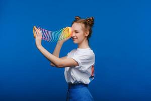 magnifique Jeune fille en jouant avec une arc en ciel moulant, une jouet de sa enfance sur une bleu Contexte photo