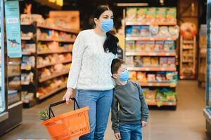 mère et fils sont achats à le épicerie magasin. elles ou ils porter masques pendant quarantaine. coronavirus pandémie .coved-19 éclair. le épidémie de le virus. photo