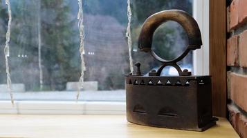 ancienne fonte pour le repassage du linge. sur le rebord de la fenêtre, il y a des accessoires pour la maison du siècle dernier comme décor à l'intérieur du restaurant. fer vintage rouillé sur charbon de bois photo