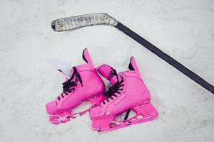 rose patins et le hockey bâton mensonge sur le neige photo