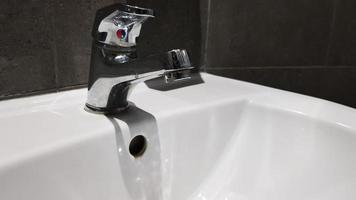 lavabo en céramique blanche avec robinet chromé dans les toilettes avec carrelage gris photo