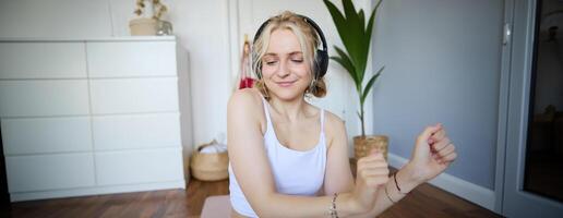 proche en haut de athlétique Jeune femme, mignonne femelle modèle dans sans fil écouteurs, dansant à préféré chanson, écoute à la musique dans écouteurs photo