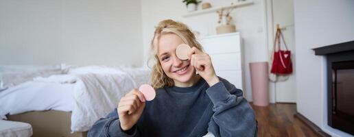 portrait de Jeune femme bavardage sur vivre courant à propos se maquiller, est assis sur sol dans chambre à coucher, montrant beauté des produits à suiveurs photo