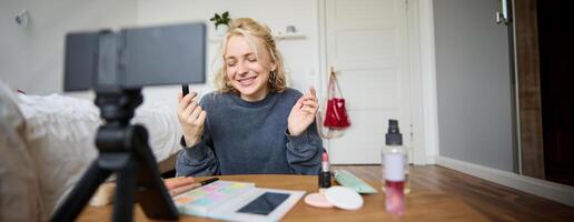 portrait de Jeune contenu fabricant, femme blogueur enregistrement une sur numérique caméra, montrant rouge à lèvres Couleur à sa suiveurs, création mode de vie vlog pour social médias Compte photo