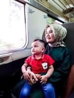 une bambin garçons premier expérience a été profiter une train voyage avec le sien grand-mère photo