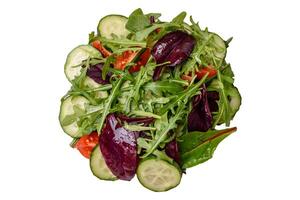 délicieux Frais salade avec roquette, épinard, concombre et Cerise tomates dans une céramique assiette photo