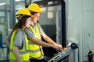 tous les deux de Jeune usine ouvrier portant une difficile chapeau à la recherche à une ordinateur écran utilisé à contrôle production. photo