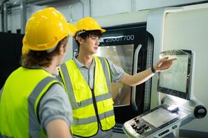 retour vue de groupe Jeune usine ouvrier portant une difficile chapeau à la recherche à une ordinateur écran utilisé à contrôle production. photo