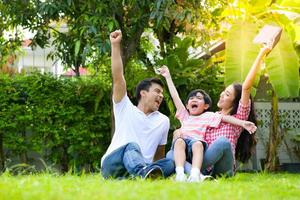 une jeune famille heureuse passe du temps à jouer ensemble dans le jardin à l'avant de la maison les vacances.