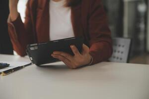 coup de une asiatique Jeune affaires femelle travail sur portable dans sa poste de travail. photo