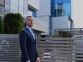 une homme d'affaire dans affaires tenue des stands pensivement, avec un Bureau bâtiment toile de fond. le homme d'affaires pose reflète le sien stratégique pensée. cette scène capture le homme d'affaires professionnalisme photo