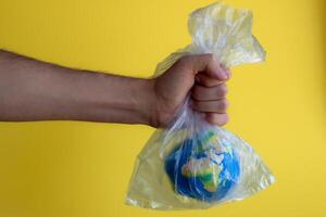 une main en portant une Plastique sac avec une petit Terre dans il photo