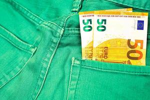 argent, achats, planque. deux 50 euro billet de banque dans vert jeans photo