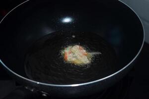 le processus de mélange brut des légumes et blé farine est frit sur une friture la poêle photo