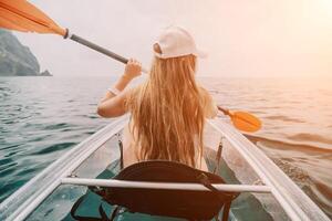 femme dans kayak retour voir. content Jeune femme avec longue cheveux flottant dans transparent kayak sur le cristal clair mer. été vacances vacances et de bonne humeur femelle gens relaxant ayant amusement sur le bateau photo