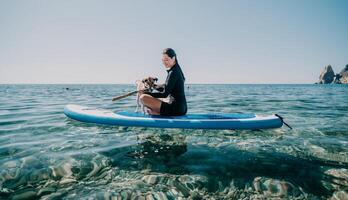 mer femme souper. silhouette de content positif Jeune femme avec sa chien, surfant sur souper planche par calme l'eau surface. idyllique le coucher du soleil. actif mode de vie à mer ou rivière. été vacances avec animaux domestiques. photo