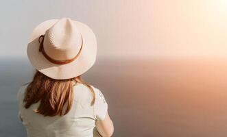 femme Voyage mer. content touristique dans chapeau prendre plaisir prise image en plein air pour souvenirs. femme voyageur posant sur le plage à mer entouré par volcanique montagnes, partage Voyage aventure périple photo