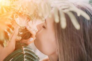 beauté portrait de content femme fermer. Jeune fille odeur chinois acacia rose épanouissement fleurs. portrait de Jeune femme dans épanouissement printemps, été jardin. romantique ambiance. femelle et la nature photo