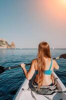 femme dans kayak retour voir. content Jeune femme avec longue cheveux flottant dans kayak sur calme mer. été vacances vacances et de bonne humeur femelle gens relaxant ayant amusement sur le bateau. photo