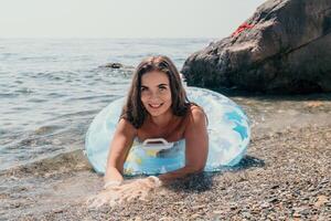 femme été mer. content femme nager avec gonflable Donut sur le plage dans été ensoleillé jour, entouré par volcanique montagnes. été vacances concept. photo