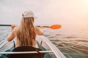 femme dans kayak retour voir. content Jeune femme avec longue cheveux flottant dans transparent kayak sur le cristal clair mer. été vacances vacances et de bonne humeur femelle gens relaxant ayant amusement sur le bateau photo