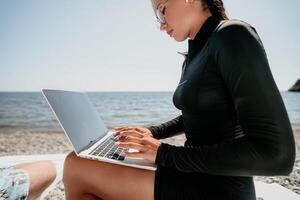 femme portable mer. travail à distance sur rivage. content réussi dame, pigiste travail sur mer plage, soulage stress de travail à restaurer la vie équilibre. free-lance, éloigné travail sur vacances photo