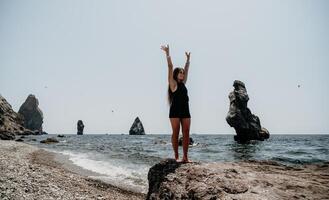 femme été Voyage mer. content touristique dans chapeau prendre plaisir prise image en plein air pour souvenirs. femme voyageur posant sur le plage à mer entouré par volcanique montagnes, partage Voyage aventure périple photo