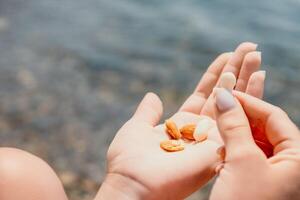 femme en mangeant laiteux amande des noisettes. une Jeune caucasien femme couper Frais vert amande après Matin aptitude yoga près mer. seulement mains sont visiblement. en bonne santé végétalien aliments. lent mouvement. proche en haut photo