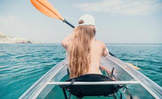 femme dans kayak retour voir. content Jeune femme avec longue cheveux flottant dans transparent kayak sur le cristal clair mer. été vacances vacances et de bonne humeur femelle gens relaxant ayant amusement sur le bateau photo