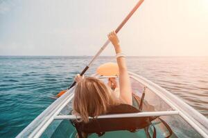 femme dans kayak retour voir. content Jeune femme avec longue cheveux flottant dans transparent kayak sur le cristal clair mer. été vacances vacances et de bonne humeur femelle gens relaxant ayant amusement sur le bateau photo