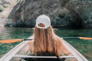 femme dans kayak retour voir. content Jeune femme avec longue cheveux flottant dans transparent kayak sur le cristal clair mer. été vacances vacances et de bonne humeur femelle gens relaxant ayant amusement sur le bateau photo