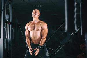 bodybuilder démontrer croisement des exercices dans le salle de sport. photo