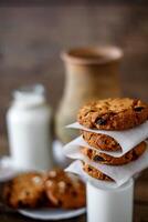 fait maison flocons d'avoine biscuits avec des noisettes et raisins secs et verre de Lait sur foncé en bois arrière-plan, fermer, sélectif concentrer photo