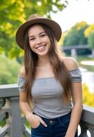 caucasien femme autour 25 ans vieux avec longue marron cheveux portant une chapeau, une gris hors de l'épaule haut, et accessoires, souriant, avec une pont et des arbres dans photo