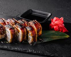 Canada anguille Sushi Rouleaux avec Saumon sur une pierre assiette photo