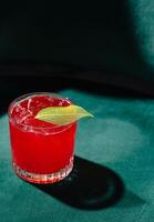 rafraîchissant rouge cocktail avec citron vert garnir sur vert velours photo