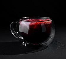 élégant verre de rouge thé sur foncé Contexte photo