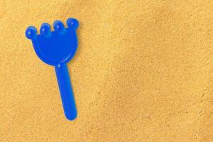 Vue rapprochée du râteau de sable bleu isolé sur la plage de sable. espace de copie ajouté pour le texte. photo