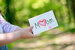 peu fille donnant sa main l'écriture salutation carte à sa maman. photo