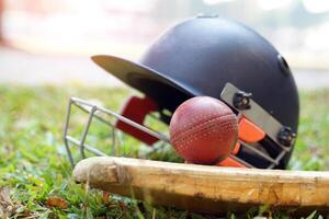 l'équipement de cricket est une balle de cricket, une batte de cricket, un casque de cricket sur fond d'herbe. mise au point douce et sélective. photo