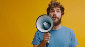 Jeune barbu homme dans bleu chemise en portant mégaphone sur Jaune Contexte photo