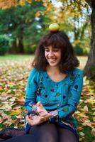 une fille dans une robe avec des ballons mensonges sur le sol couvert avec l'automne feuilles photo