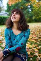 une fille dans une robe avec des ballons mensonges sur le sol couvert avec l'automne feuilles photo