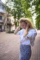 magnifique milieu âge femme dans années 70, Années 80 style vêtements s'étire après travail sur une Soleil trempé ruelle photo