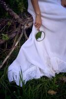 magnifique femme dans blanc ancien robe avec train et en portant ancien miroir dans printemps jardin à le coucher du soleil photo