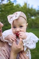 bébé fille mange des fraises dans sa de la mère bras photo