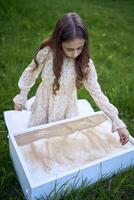 une mignonne fille dans une pastel robe dessine avec le sable sur une spécial table photo
