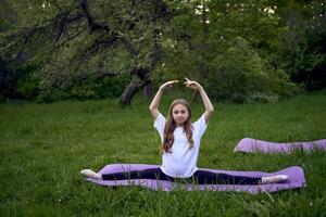 le fille est séance dans ficelle sur une yoga tapis dans le jardin photo